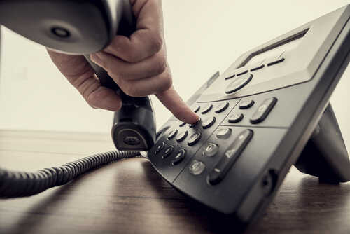 Closeup,Of,Male,Hand,Holding,Telephone,Receiver,And,Dialing,A
