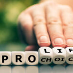 Hand switching dice between "pro life" and "choice".