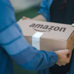 Two people exchanging an Amazon package, outdoors.