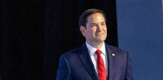 Man in suit and red tie on stage