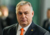 Hungary Breaks Promise—€90 Billion Aid VANISHES Man wearing suit with orange tie indoors
