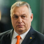 Hungary Breaks Promise—€90 Billion Aid VANISHES Man wearing suit with orange tie indoors