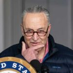 Schumer Defies 83% of Americans Man speaking at a podium with a thoughtful expression