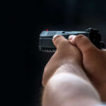 Person holding a black handgun in firing position