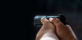 Person holding a black handgun in firing position