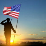 Community’s Powerful Message: Veterans Are Family soldier holding flag facing sunset