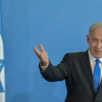 War Escalates: Iran’s Death Vow on Netanyahu Man speaking next to Israeli flag.