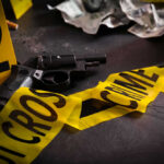 Gun surrounded by crime scene tape and evidence markers