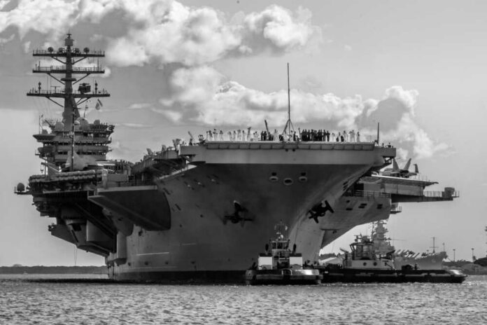 Large aircraft carrier being assisted by tugboats in the ocean