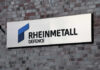 Sign displaying Rheinmetall Defence logo on a brick wall