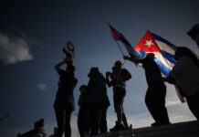 Russian Oil Tanker Nears Cuba—US Coast Guard Stands Down Silhouetted figures holding a trophy and Cuban flags during a celebration