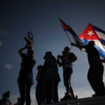 Cuba COLLAPSE Imminent — Trump Moves In Silhouetted figures holding a trophy and Cuban flags during a celebration
