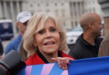 A woman with blonde hair and a red jacket participating in a protest