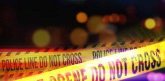 Yellow police tape marking a crime scene with blurred lights in the background