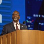 A business leader speaking at a podium during a conference