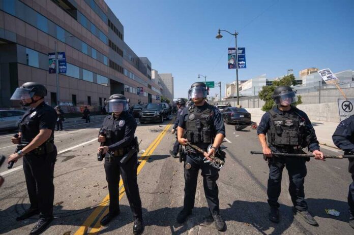 shutterstock_2639522715.jpg Police officers in riot gear standing on a street during a protest