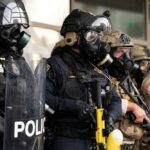 DHS Leaders Blocked Probes: Shocking Watchdog Claims Police officers in tactical gear and gas masks standing in formation