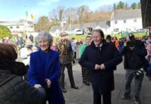 A group of people at a public event, with two individuals shaking hands and smiling.