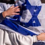 People holding an Israeli flag together, showcasing unity and cultural pride