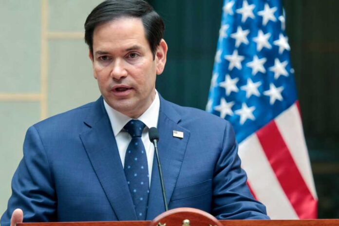 Marco Rubio speaks_2581735273.jpg A man in a blue suit speaking into a microphone with an American flag in the background