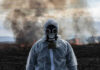 Person in gas mask standing near smoky area