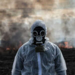 Person in gas mask standing near smoky area