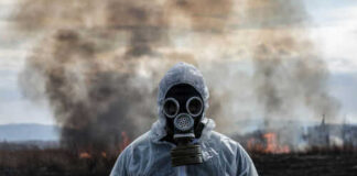 Person in gas mask standing near smoky area