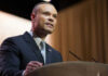 Man in suit speaking at podium with microphones
