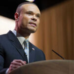 Man in suit speaking at podium with microphones