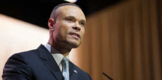 Man in suit speaking at podium with microphones