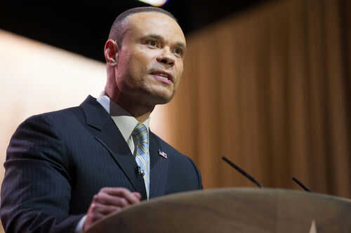 Man in suit speaking at podium with microphones
