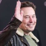 Man in leather jacket smiling and waving