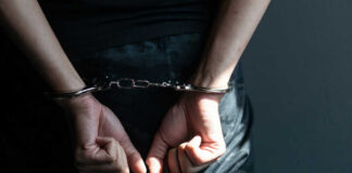 Person with hands cuffed behind back in handcuffs