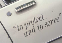 Close-up of a police vehicle door with the phrase 'to protect and to serve'