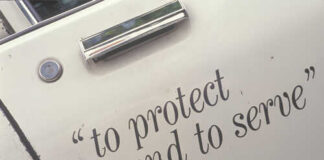 Close-up of a police vehicle door with the phrase 'to protect and to serve'