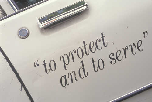 Close-up of a police vehicle door with the phrase 'to protect and to serve'