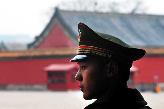 A military guard in uniform standing in profile against a historical building
