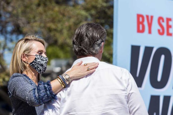 shutterstock_2036606903.jpg A woman in a mask places her hand on a man's shoulder at a political event