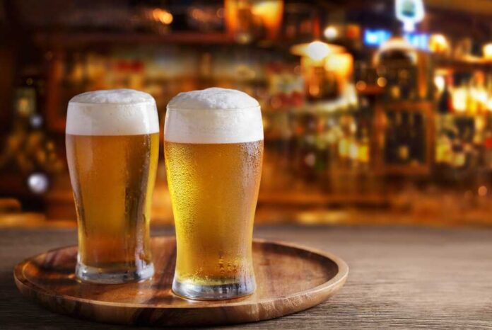 Two glasses of beer on a wooden tray in a bar setting