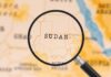 A magnifying glass focusing on the country Sudan on a map
