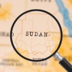 A magnifying glass focusing on the country Sudan on a map