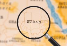 A magnifying glass focusing on the country Sudan on a map