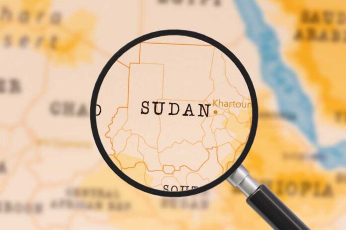 A magnifying glass focusing on the country Sudan on a map