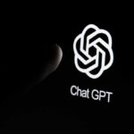 Close-up of a hand reaching towards the ChatGPT logo on a smartphone screen