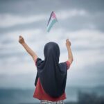 Bridgeview’s Bold Move: ‘Little Palestine’ Sign A young person holding a flag against a cloudy sky