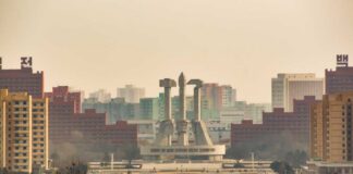 View of a large monument surrounded by buildings in Pyongyang
