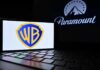 Warner Bros logo displayed on a smartphone with Paramount logo in the background