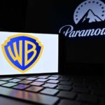 Warner Bros logo displayed on a smartphone with Paramount logo in the background