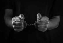 Hands holding handcuffs in a black and white image