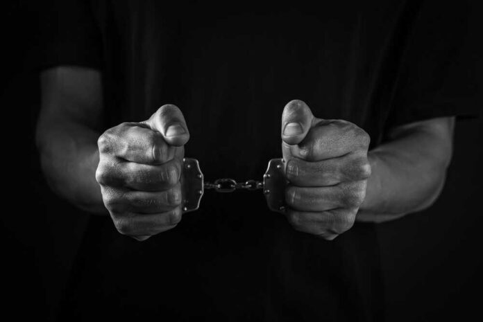 Hands holding handcuffs in a black and white image
